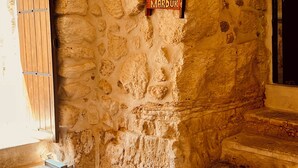 A stone-walled room with a sign reading "MARDUK" and a wooden door. - Mons Masius Hotel (Midyat)