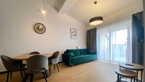 Ein modernes Wohnzimmer mit Esstisch, Stühlen, einer Couch und einem kleinen Beistelltisch.