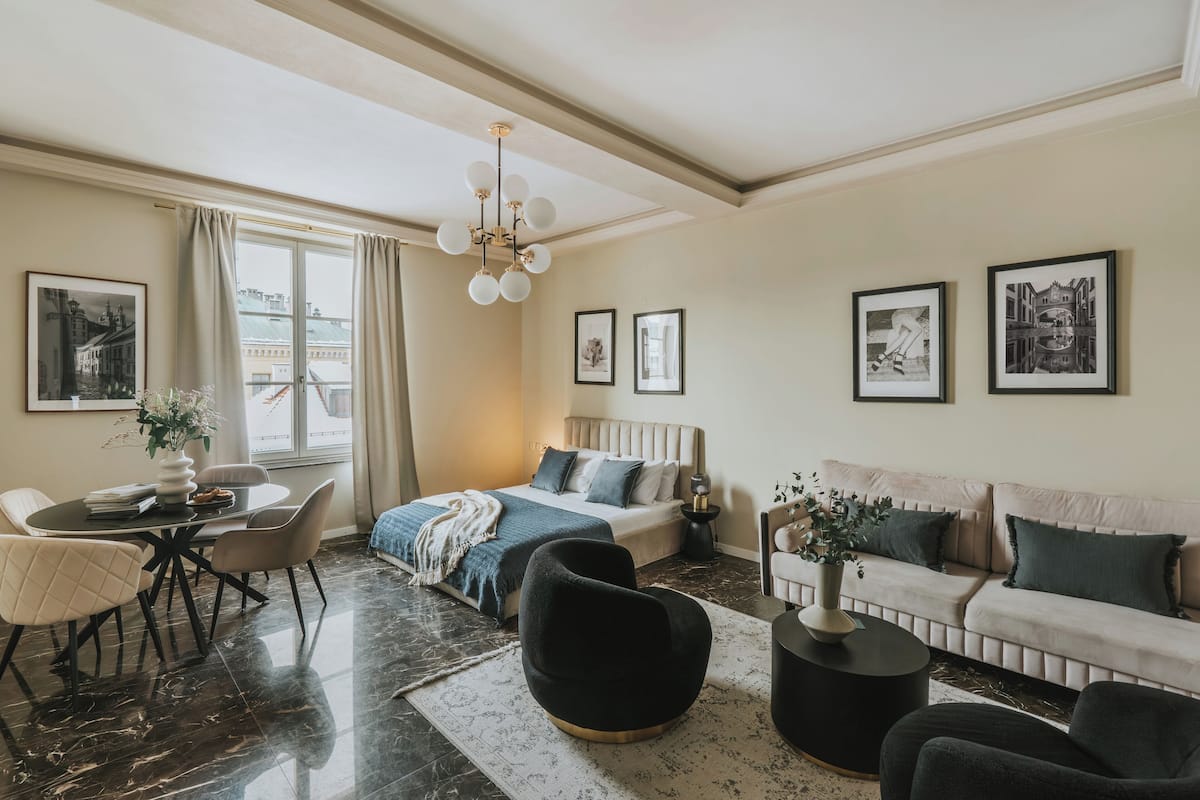 Een moderne hotelkamer met een bed, een bank, een eethoek en kunstwerken aan de muren.