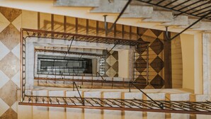 A staircase with a metal railing and a geometric patterned wall. - Bogoria House (Kraków)