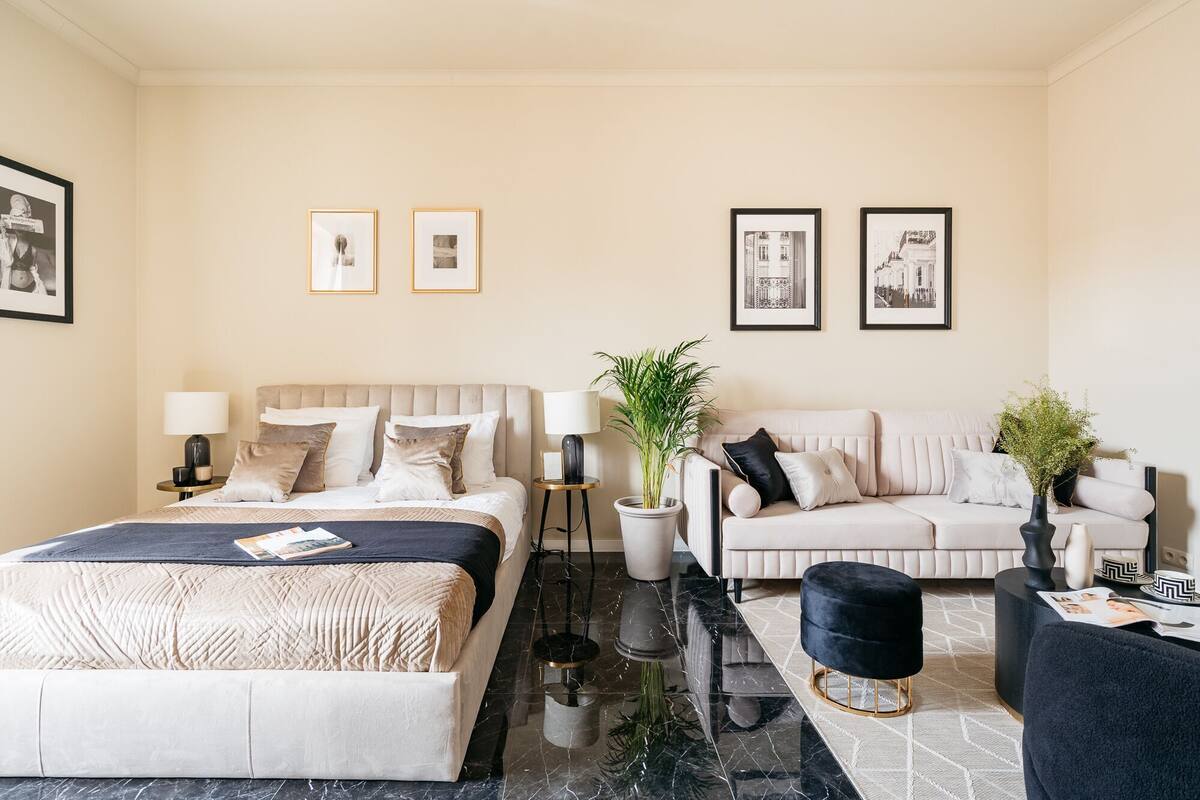 Een hotelkamer met een bed, een bank, een salontafel, een bijzettafeltje en twee potplanten.