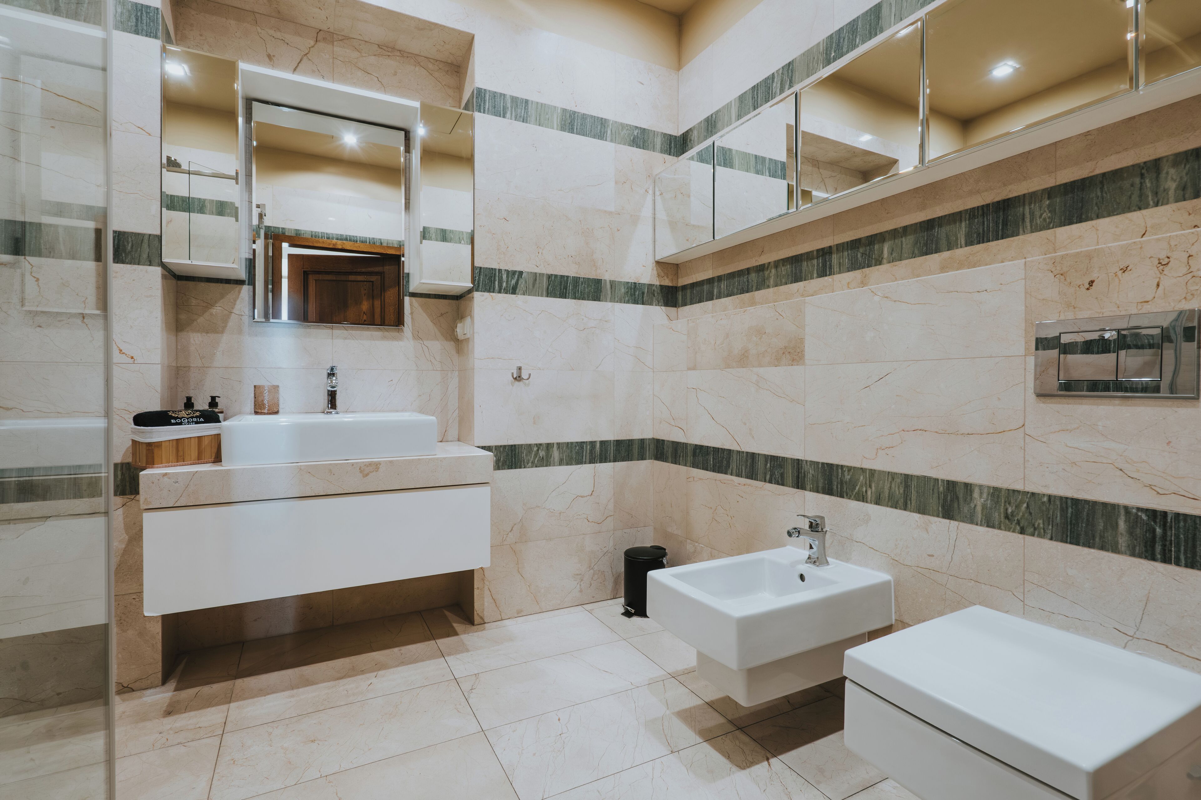 A modern bathroom with a large mirror, a vanity with a sink, and a separate pedestal sink.