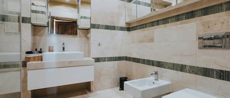 A modern bathroom with a large mirror, a vanity with a sink, and a separate pedestal sink.