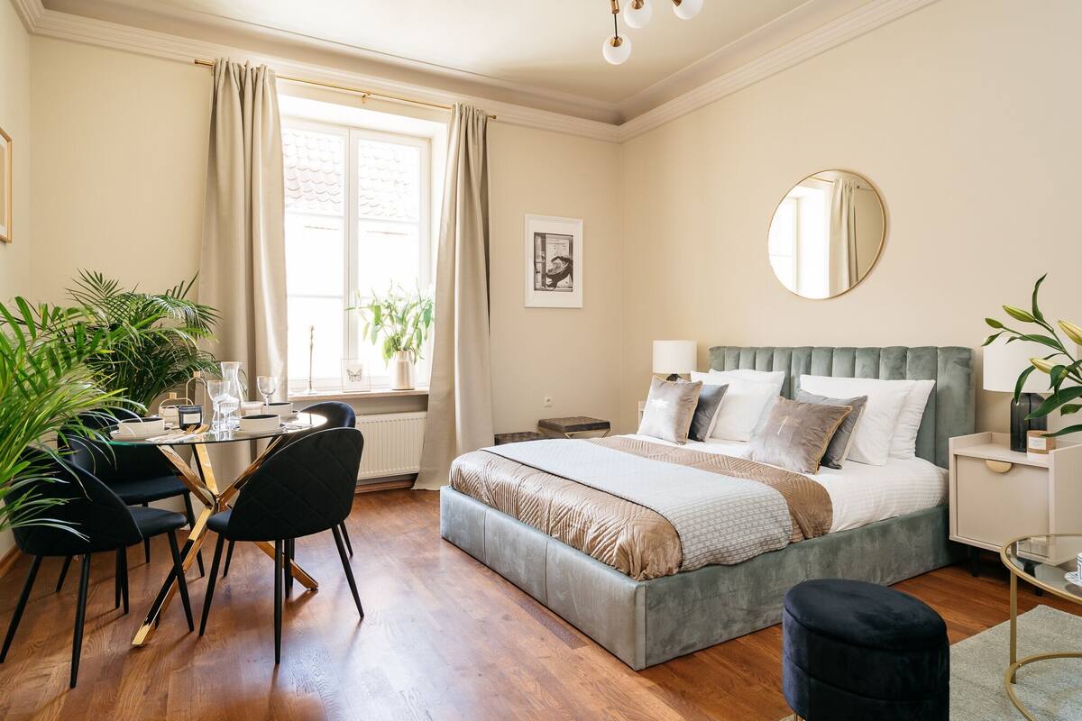Een goed verlichte slaapkamer met een bed, nachtkastje en een raam met gordijnen.