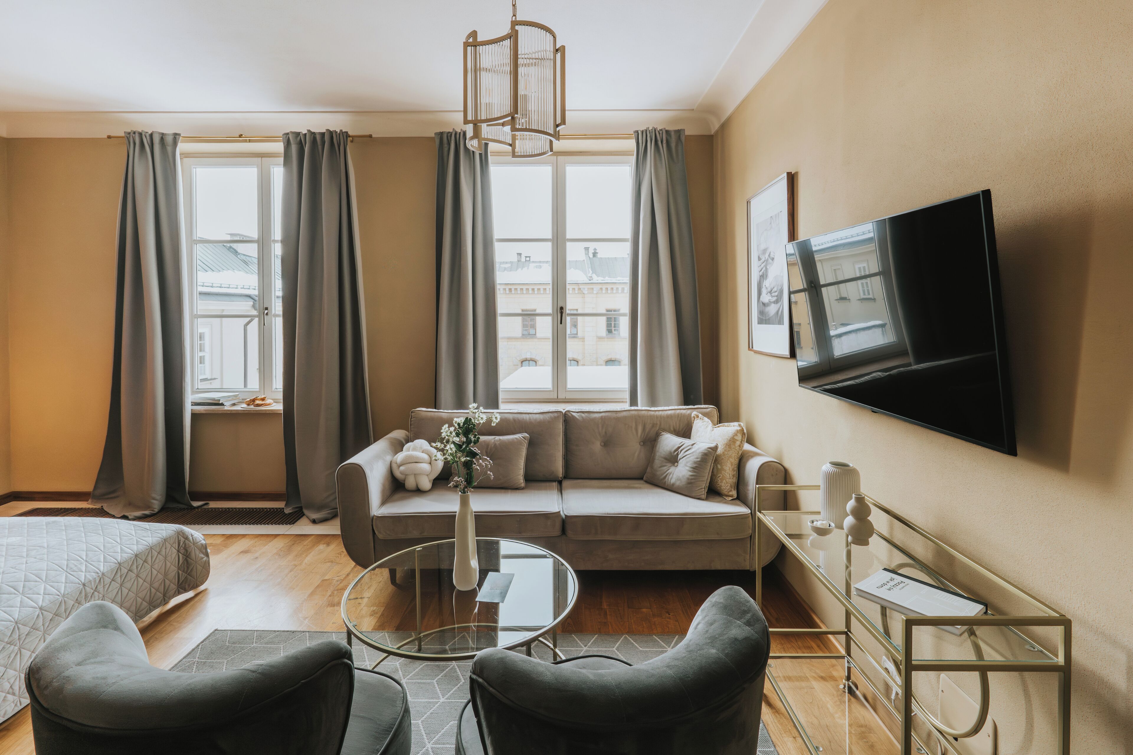 A modern living room with a sofa, a glass coffee table, and a TV mounted on the wall.