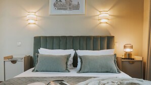 A neatly made bed with a quilted bedspread, two pillows, and a bedside table with a lamp and a book. - Bogoria House (Kraków)