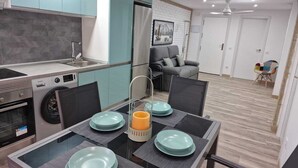 Une cuisine moderne dotée d’un four encastré, d’un évier et d’un coin repas avec une table et des chaises en verre.