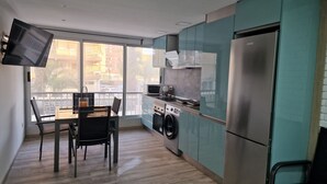 Une cuisine moderne équipée d’un lave-linge intégré, d’un réfrigérateur et d’un coin repas avec une table et des chaises.