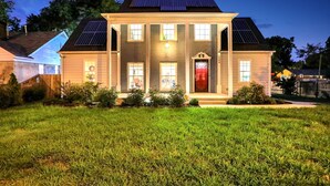 A two-story house with a front porch, solar panels, and a red door. - Luxury Memphis Musical Estate! Pool, Games! (Memphis)