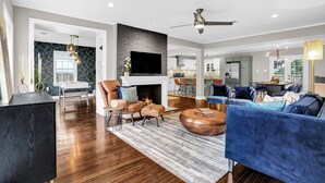 A spacious living room with a fireplace, a television, and a ceiling fan. - Luxury Memphis Musical Estate! Pool, Games! (Memphis)