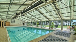 A covered swimming pool with clear water, surrounded by lounge chairs and potted plants. - Spacious Cheriton Home: 8 Mi to Cape Charles! (Cheriton)