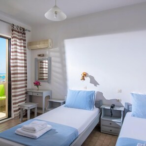 A hotel room with two beds, a desk, a chair, a mirror, and a view of the sea. - Smaragdine Beach (Hersonissos)