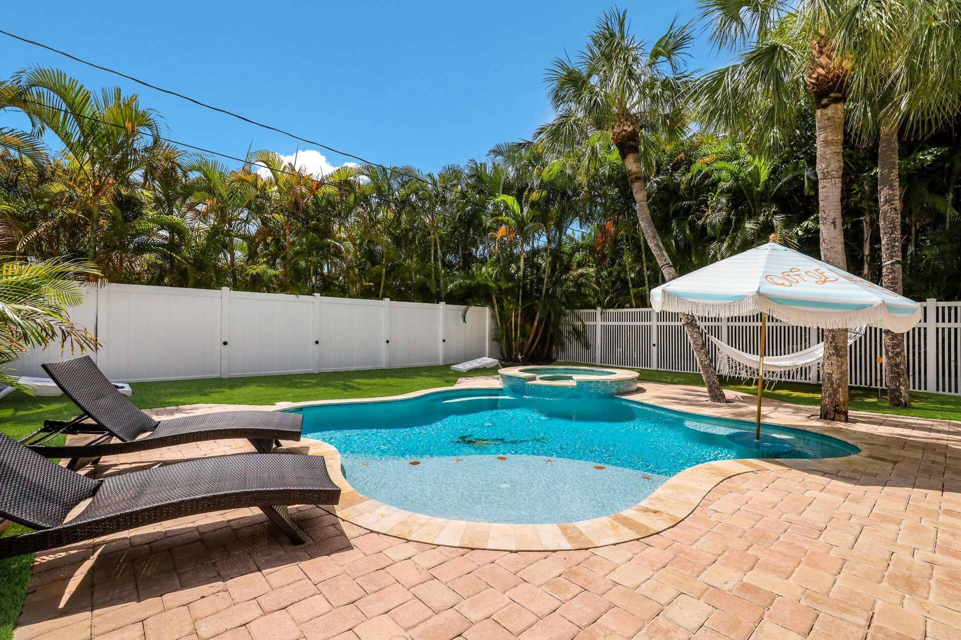 Un jardin avec une piscine, des chaises longues et un hamac.