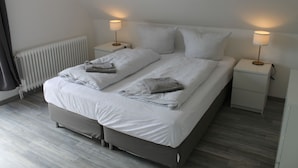 Un dormitorio moderno con una cama grande, dos mesitas de noche y un radiador.