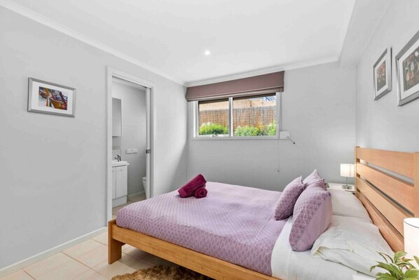 Un dormitorio con cama, ventana, puerta y un baño pequeño.