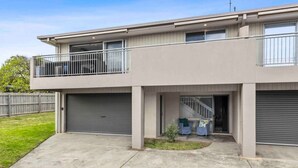 Ein zweistöckiges Wohnhaus mit Balkon, Garage und kleinem Vorgarten.