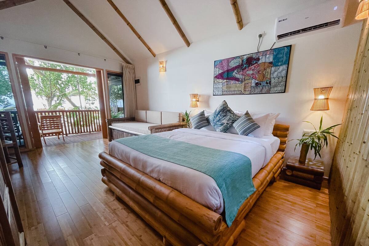 Un dormitorio amplio con una cama grande, cabecera de madera y un balcón con baranda de madera.