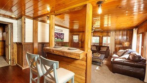 A wooden interior with a dining area, a sofa, and a television. - Newly Remodeled Private Cabin - Hot Tub, Firepit, Video Arcade Game (Sevierville)