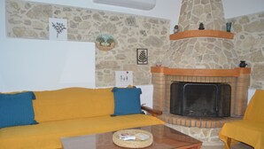 Un salon avec une cheminée en pierre, un canapé jaune et une table basse.