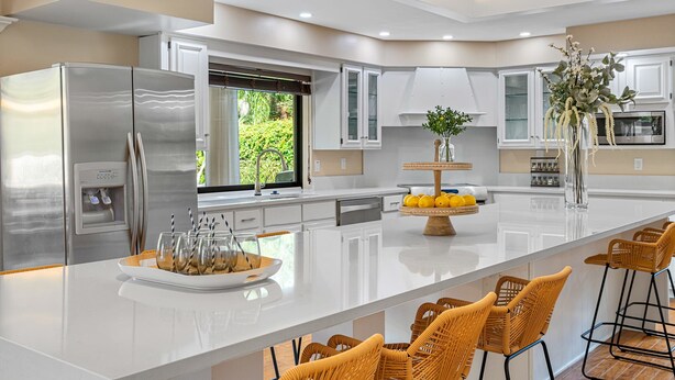A modern kitchen with a large island, stainless steel appliances, and wicker bar stools. - 8 BR Heated Pool & Soccer Field (Largo)