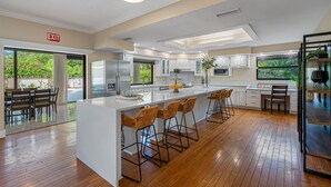 A modern kitchen with a large island, bar stools, and a view of greenery outside. - 8 BR Heated Pool & Soccer Field (Largo)
