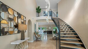 A spacious foyer with a modern staircase, a decorative wall, and comfortable seating. - 8 BR Heated Pool & Soccer Field (Largo)