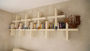 Eine an der Wand befestigte Bücherregal mit mehreren kreuzförmigen Ablagen, die Bücher und ein kleines Schiffmodell beherbergen.