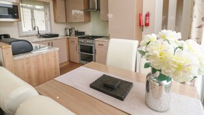 Una cocina compacta con microondas, estufa y horno, un comedor con mesa y sillas, y un florero con flores.