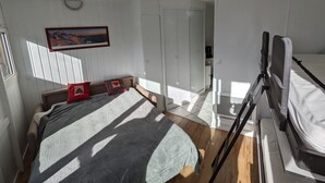 Huoneessa on sänky, tuoli, työpöytä ja ikkuna.