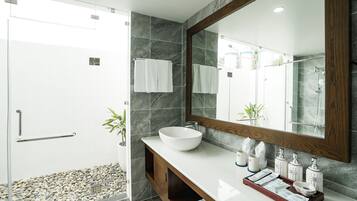 A modern bathroom with a large mirror, a white vessel sink, and a wooden vanity.