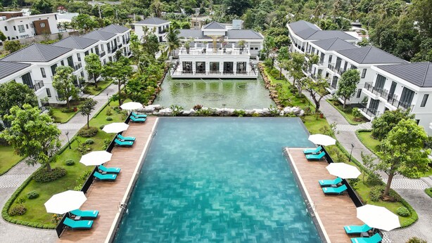 Une grande piscine rectangulaire dont le fond est décoré d’un motif en chevrons, entourée de chaises longues et de parasols.