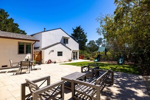 Une maison avec un patio, un espace salon extérieur et un toboggan.