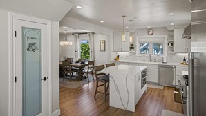 A modern kitchen with white cabinetry, a marble island, and stainless steel appliances. - Iaorana: Newly remodeled luxury 3 bedroom with Ocean Views (Carmel)