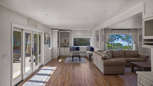A spacious living area with a sofa, a coffee table, and a view through large windows. - Iaorana: Newly remodeled luxury 3 bedroom with Ocean Views (Carmel)