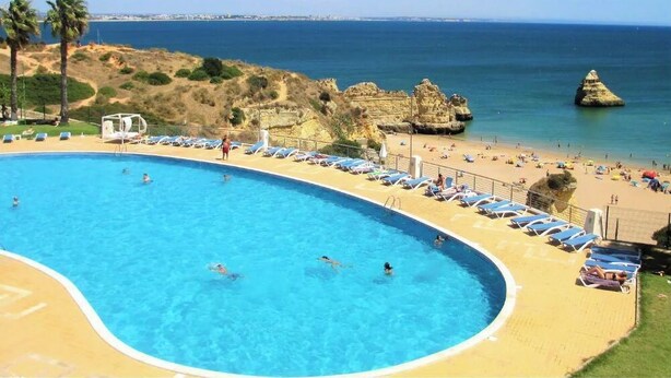 A swimming pool with people swimming, a beach area with sun loungers, and a rocky coastline with a clear view of the sea. - Coastal Escape with Backyard Beach, Inema INES (Lagos)
