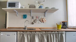 Una cocina con lavavajillas, microondas, cafetera y una percha para ollas.