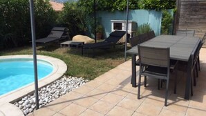 Une terrasse avec une piscine, du mobilier d’extérieur et une vue sur les montagnes.