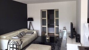 Un salon moderne avec un canapé, une table basse et un téléviseur.