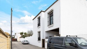 A two-story building with a white facade, a parked car, and a van in front. - Apartment 'Clara 1' close to the Sea with Terrace & Wi-Fi (Conil)