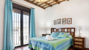 A bedroom with a bed, curtains, a nightstand, a lamp, and wall art. - Apartment 'Clara 1' close to the Sea with Terrace & Wi-Fi (Conil)