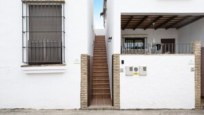 A white building with a staircase leading to a covered area, a barred window, and a no parking sign. - Apartment 'Clara 1' close to the Sea with Terrace & Wi-Fi (Conil)