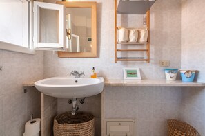 Une salle de bain équipée d’un lavabo, d’un miroir, d’un porte-serviettes et d’un panier.