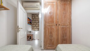 Una stanza con due letti, un armadio in legno, una parete in pietra e un piccolo tavolo con una lampada.