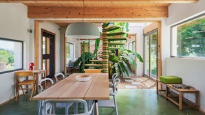 Een moderne eetruimte met een houten tafel, witte stoelen en een groene bank.