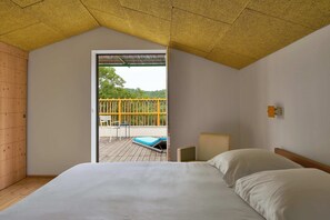 Ein Schlafzimmer mit einem großen Bett, einem Holzschrank und Blick auf eine Terrasse mit Tisch und Stühlen.