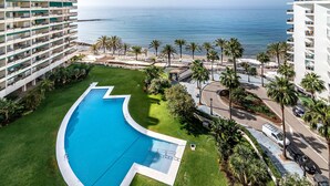 Un hotel con piscina, palmeras y vistas al océano.
