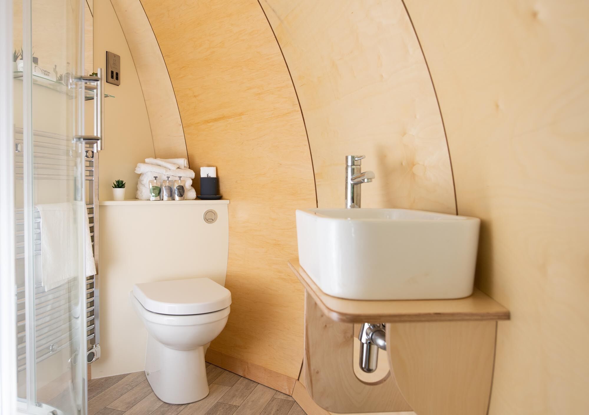 A compact bathroom with a toilet, a sink, and a shower enclosure.