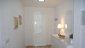 A hallway with a white door, a small rug, a mirror, and a lamp on a dresser. - Villa 'Nala' with Pool and Wi-Fi (Mazarrón)