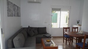 A living room with a sofa, coffee table, dining table with chairs, and a window with bars. - Villa 'Nala' with Pool and Wi-Fi (Mazarrón)