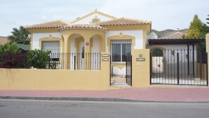 A yellow building with a tiled roof, a gated entrance, and a small garden area. - Villa 'Nala' with Pool and Wi-Fi (Mazarrón)